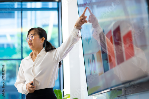 Presentation - Asian business woman people giving presentation and Report pointing at projector or TV screen. People Work in Business Office.