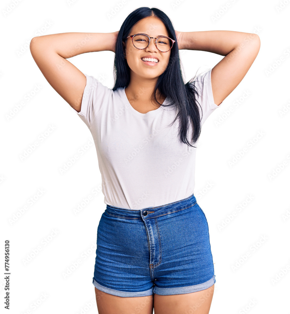 Young beautiful asian girl wearing casual clothes and glasses relaxing and stretching, arms and hands behind head and neck smiling happy Young beautiful asian girl wearing casual clothes and glasses relaxing and stretching, arms and hands behind head and neck smiling happy