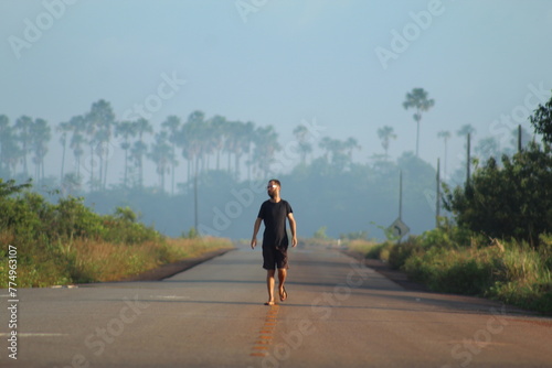homem caminhando em rodovia em Calçoene, Amapá, em amanhecer com neblina  photo