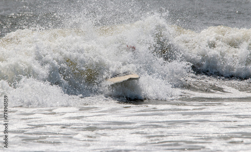 Surfboard in rough water after surfer wipes out and falls photo