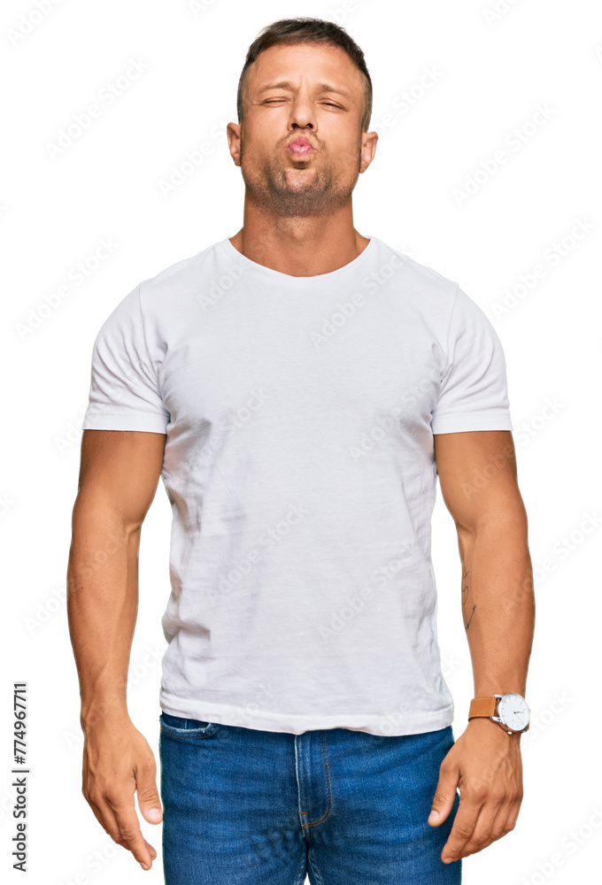 Handsome muscle man wearing casual white tshirt puffing cheeks with funny face. mouth inflated with air, crazy expression. Handsome muscle man wearing casual white tshirt puffing cheeks with funny face. mouth inflated with air, crazy expression.