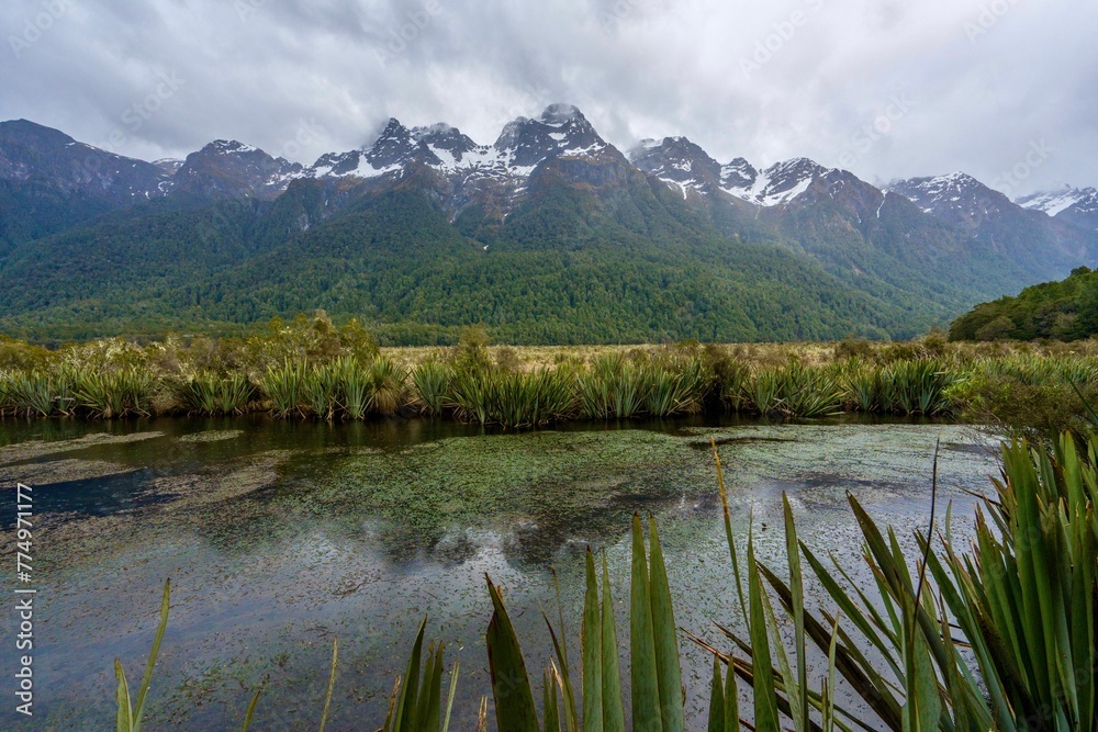 Landscape view with Mirror Lakes on a gloomy day, snowy mountains and cloudy sky background