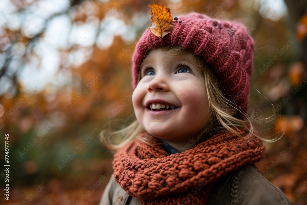 Portrait of a little girl in a hat and scarf with an autumn leaf in her hair Portrait of a little girl in a hat and scarf with an autumn leaf in her hair
