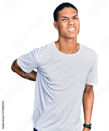 Young hispanic man wearing casual white t shirt suffering of backache, touching back with hand, muscular pain