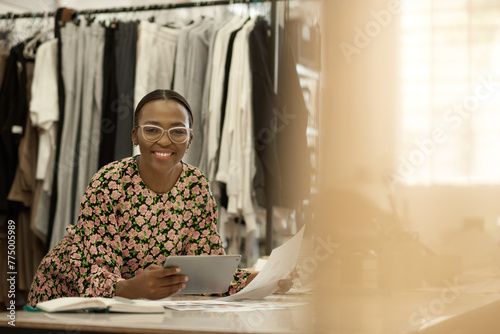 Smiling African female fashion designer working on a tablet in her studio