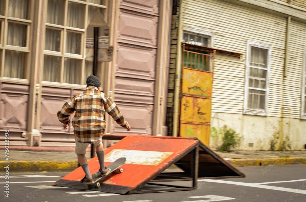 Male skateboarder doing tricks on the road with old buildings in the background