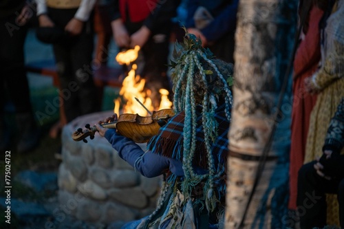 Closeup of a female playing violin next to the stone bonfire