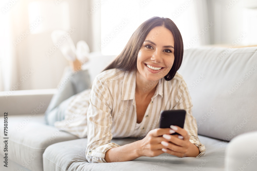 Smiling woman using smartphone on couch at home Smiling woman using smartphone on couch at home