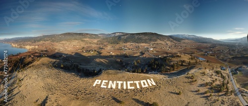 Aerial panoramic shot of the rocky mountains with a huge text 'penticton' on it photo