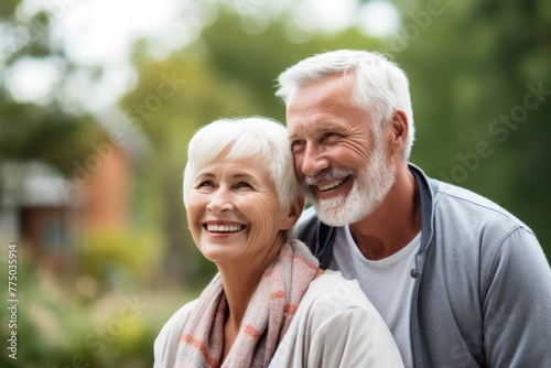 A senior couple with white hair shares a laugh together in a natural outdoor setting, radiating joy and companionship. Happy Senior Couple Enjoying a Moment Outdoors