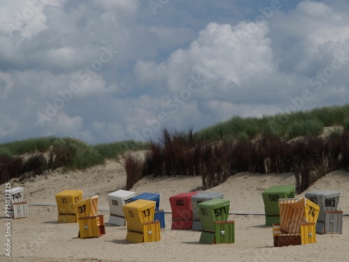 Numbered colorful beach chairs on the sand at langeoog island under cloudy sky, Germany photo