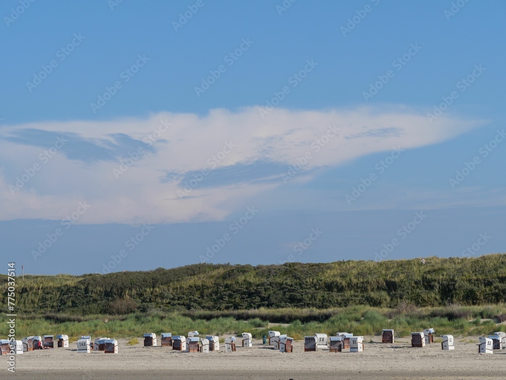 Beach chairs on Spiekeroog island under blue cloudy sky