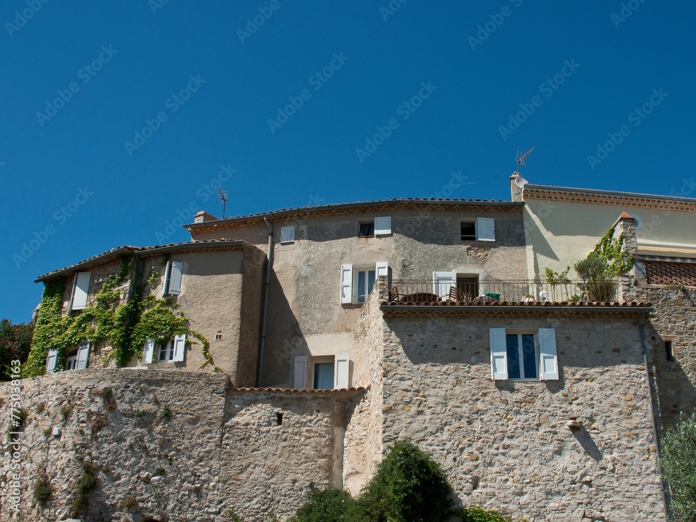 Exterior of trees under stone traditional houses with blue sky in Le Castellet, France