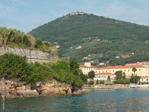 Green Coastal Italian of Spezia with stone buildings and green mountain by the water and blue sky