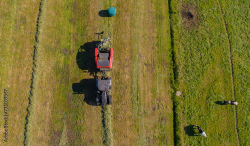 Schwarzer Treker oder Traktor mit einer roten Stroh Festkammerpresse bei der Strohernte auf einem gemähten Feld