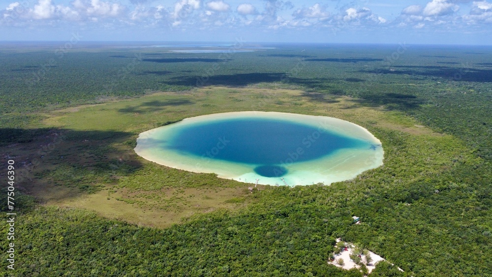 Cenote with 2 different types of blue surrounded by a forest, in Mexico, seen from above