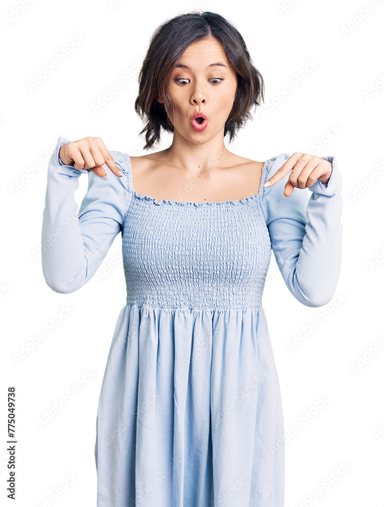 Young beautiful girl wearing casual clothes pointing down with fingers showing advertisement, surprised face and open mouth