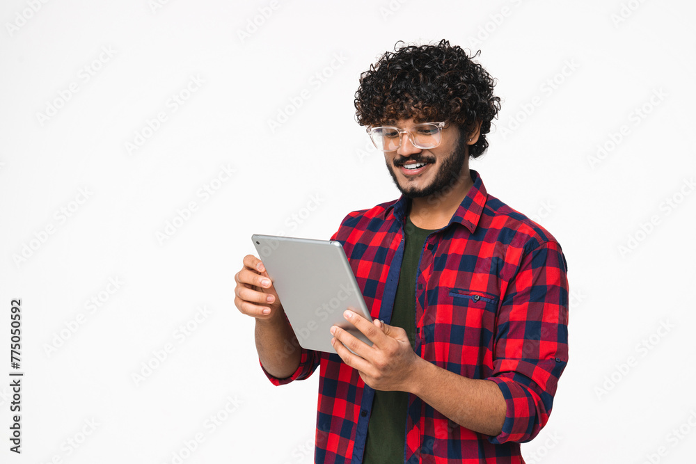 Happy young Indian freelancer suing digital tablet for remote job isolated over white background. Hindi businessman scrolling social media, doing online shopping Happy young Indian freelancer suing digital tablet for remote job isolated over white background. Hindi businessman scrolling social media, doing online shopping
