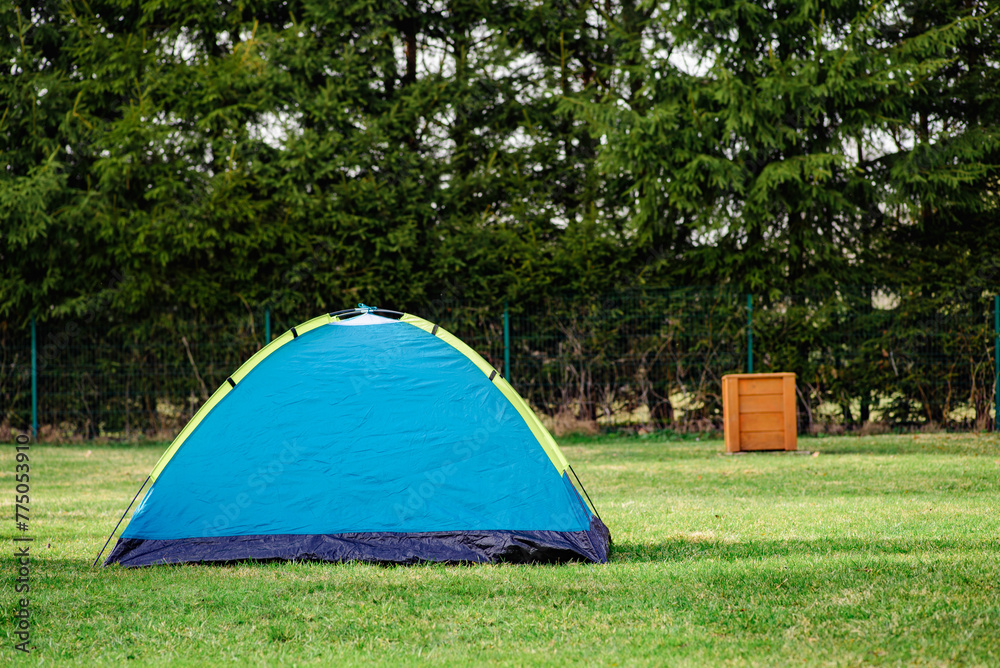 blue tent in the forest behind the trees and the dumpster blue tent in the forest behind the trees and the dumpster