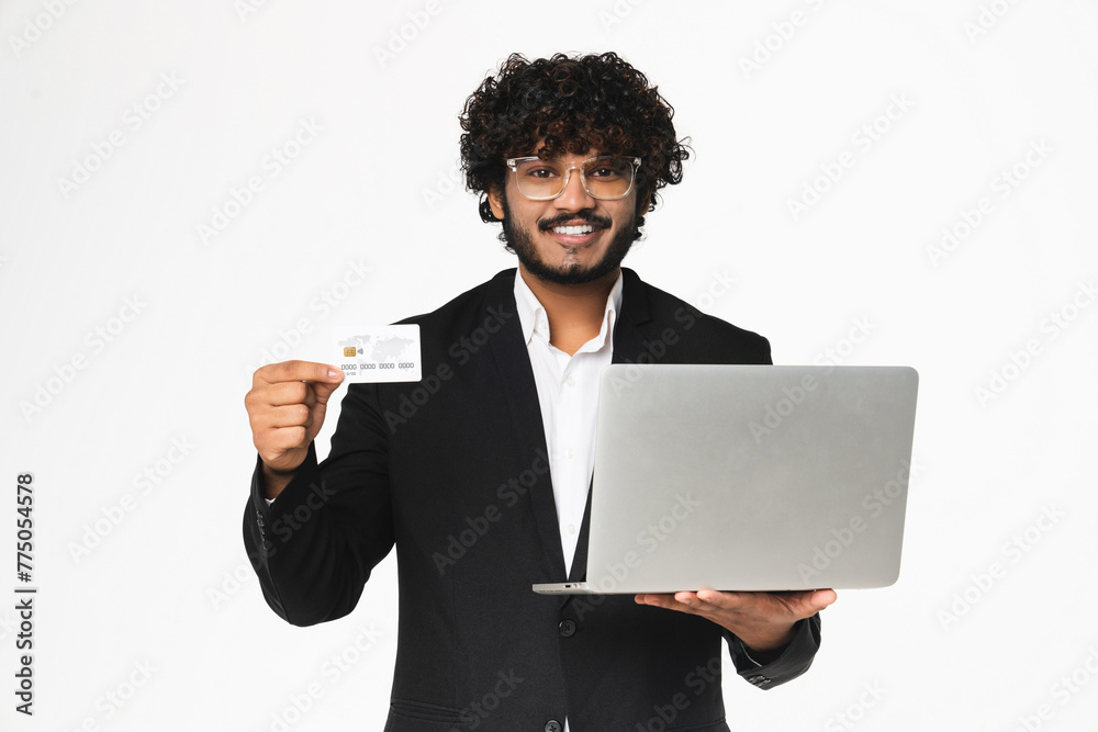 Cheerful Hindu businessman in formal tuxedo using laptop for e-banking isolated Cheerful Hindu businessman in formal tuxedo using laptop for e-banking isolated