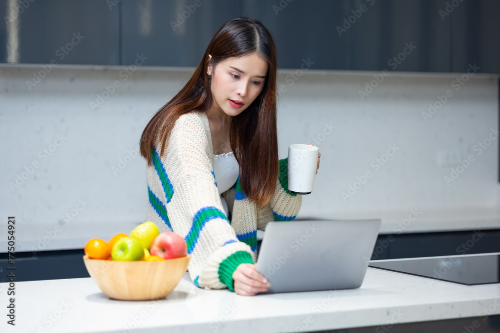 woman relaxing - Happy young teen girl using laptop computer sit at table working learning online in internet at home enjoy morning coffee in cozy house kitchen. Pretty woman wearing sweater at home woman relaxing - Happy young teen girl using laptop computer sit at table working learning online in internet at home enjoy morning coffee in cozy house kitchen. Pretty woman wearing sweater at home