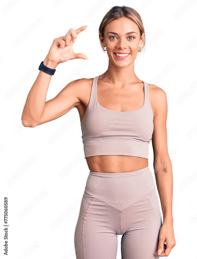 Beautiful caucasian woman wearing sportswear smiling and confident gesturing with hand doing small size sign with fingers looking and the camera. measure concept. Beautiful caucasian woman wearing sportswear smiling and confident gesturing with hand doing small size sign with fingers looking and the camera. measure concept.