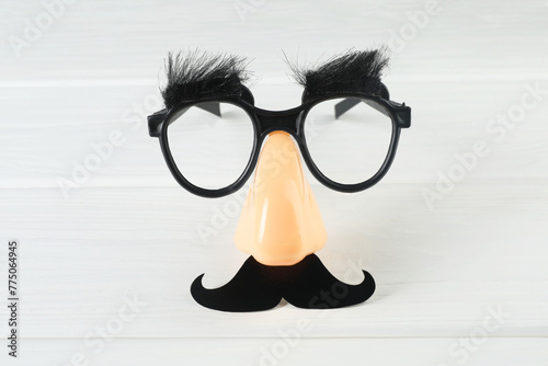 Funny mask with fake mustache, nose and glasses on white wooden background, top view