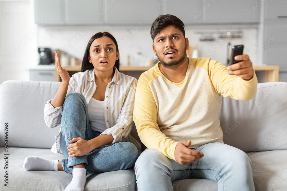 Shocked Indian Couple Reacting to News in Bright Living Room Shocked Indian Couple Reacting to News in Bright Living Room