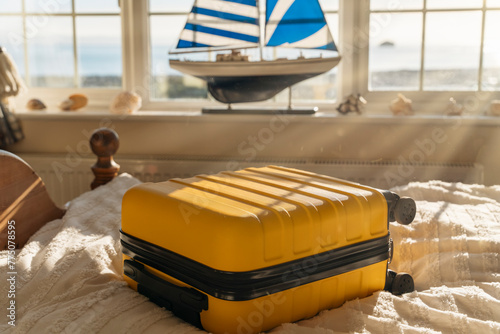 Suitcase or luggage bag on bed in a classic old hotel room with sea view Under the sun's rays © Iryna