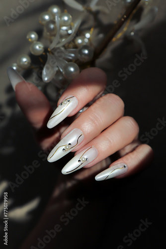 Pearl design with rhinestones on long extended nails.
