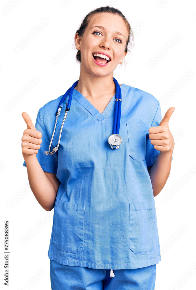 Young beautiful blonde woman wearing doctor uniform and stethoscope success sign doing positive gesture with hand, thumbs up smiling and happy. cheerful expression and winner gesture. Young beautiful blonde woman wearing doctor uniform and stethoscope success sign doing positive gesture with hand, thumbs up smiling and happy. cheerful expression and winner gesture.