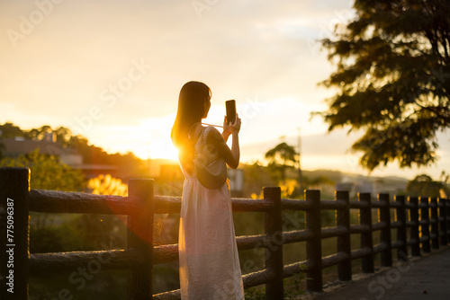 Woman use mobile phone to take photo under sunset in countryside