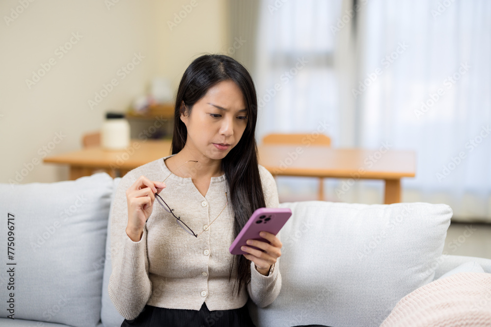 Woman suffering eyestrain trying to read on mobile phone at home Woman suffering eyestrain trying to read on mobile phone at home