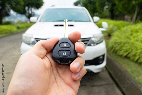 Car key in hand with car on the background. Car stuff concept.