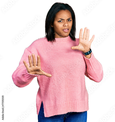 Beautiful hispanic woman wearing casual winter sweater afraid and terrified with fear expression stop gesture with hands, shouting in shock. panic concept.
