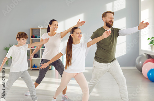 Young smiling sporty parents man and woman doing fit sport exercise with kids in gym. Happy family having workout together and home training. Fitness and healthy lifestyle concept.