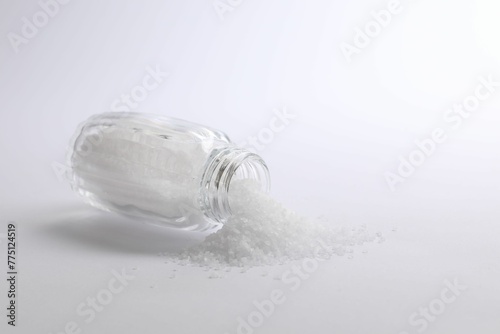 Natural salt in shaker on white background, space for text