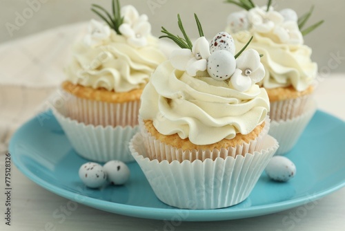 Tasty Easter cupcakes with vanilla cream on light wooden table, closeup