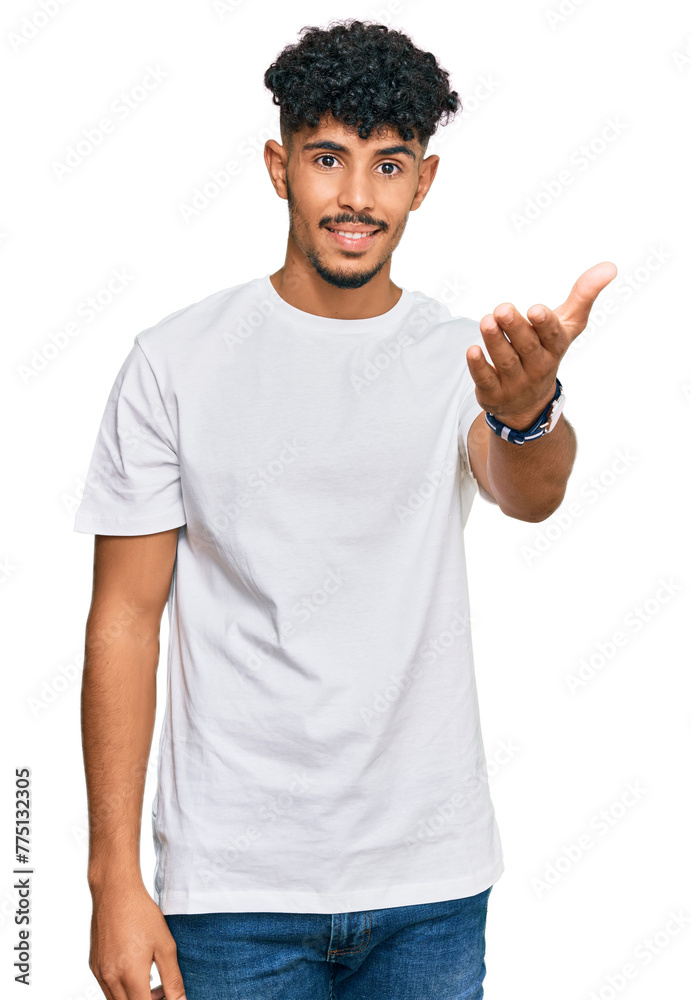 Fototapeta premium Young arab man wearing casual white t shirt smiling friendly offering handshake as greeting and welcoming. successful business.