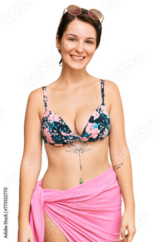 Young brunette woman with short hair wearing bikini looking positive and happy standing and smiling with a confident smile showing teeth