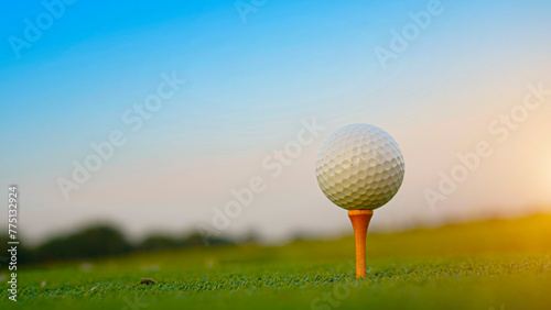 Close-up golf ball on tee with blur green bokeh background.