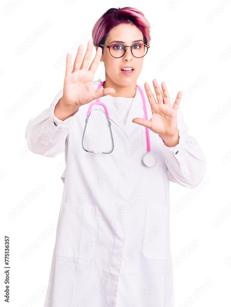 Young beautiful woman with pink hair wearing doctor uniform afraid and terrified with fear expression stop gesture with hands, shouting in shock. panic concept. Young beautiful woman with pink hair wearing doctor uniform afraid and terrified with fear expression stop gesture with hands, shouting in shock. panic concept.