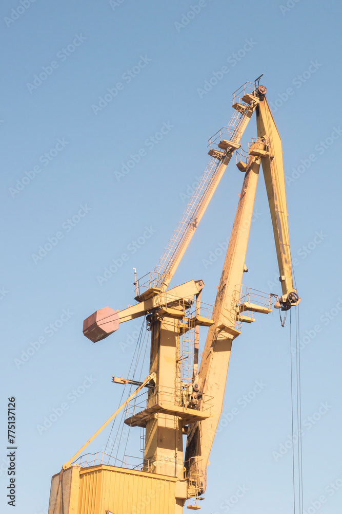 Port industrial crane at river sand unloading depot on clear sunny day