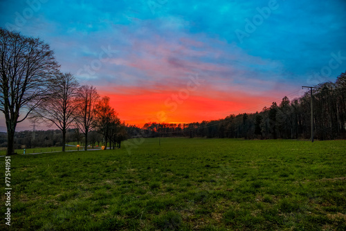 Bright red sunset Over meadows at the edge of a forest next to a road near Koblenz