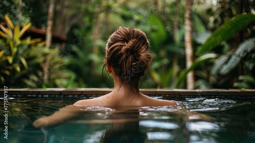 Back view of young woman relaxing in swimming pool at tropical resort. © Resi
