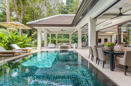 A photo of the pool and garden in front, taken from inside an ultraluxury bungalow villa with white walls in Phuket Thailand, shows a beautiful lush green yard with some trees © Kien