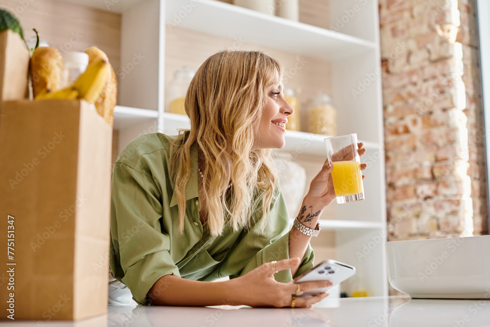 A woman sits at a kitchen table holding a glass of orange juice. A woman sits at a kitchen table holding a glass of orange juice.