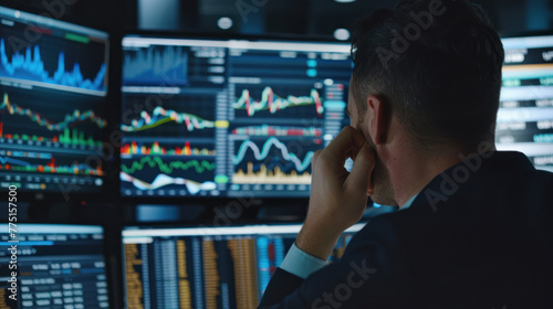 A stressed trader with hand on forehead analyzing multiple screens showing stock data