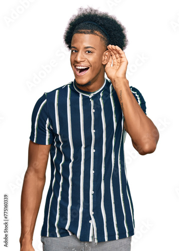 African american man with afro hair wearing casual clothes smiling with hand over ear listening an hearing to rumor or gossip. deafness concept.