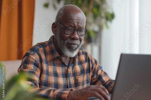 Older Man Sitting at Table Using Laptop Computer photo